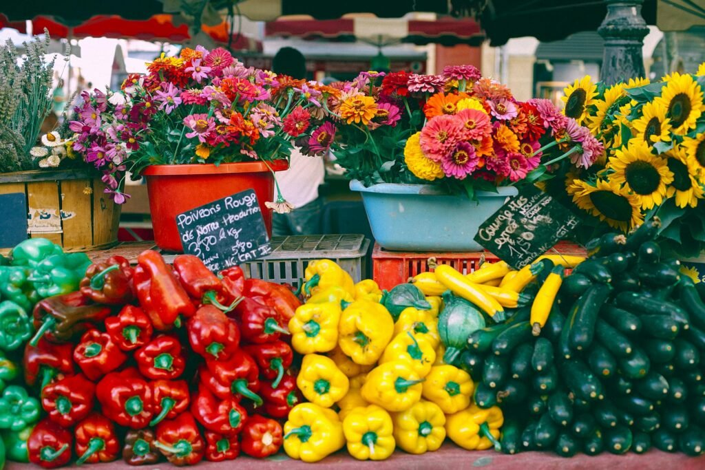 Assorted fresh pepper and cucumbers at counter with fresh gerberas and sunflowers selling at bazaar