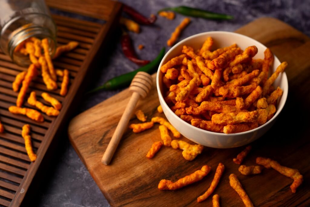 A bowl of spicy crunchy snacks on a wooden surface, perfect for junk food cravings.